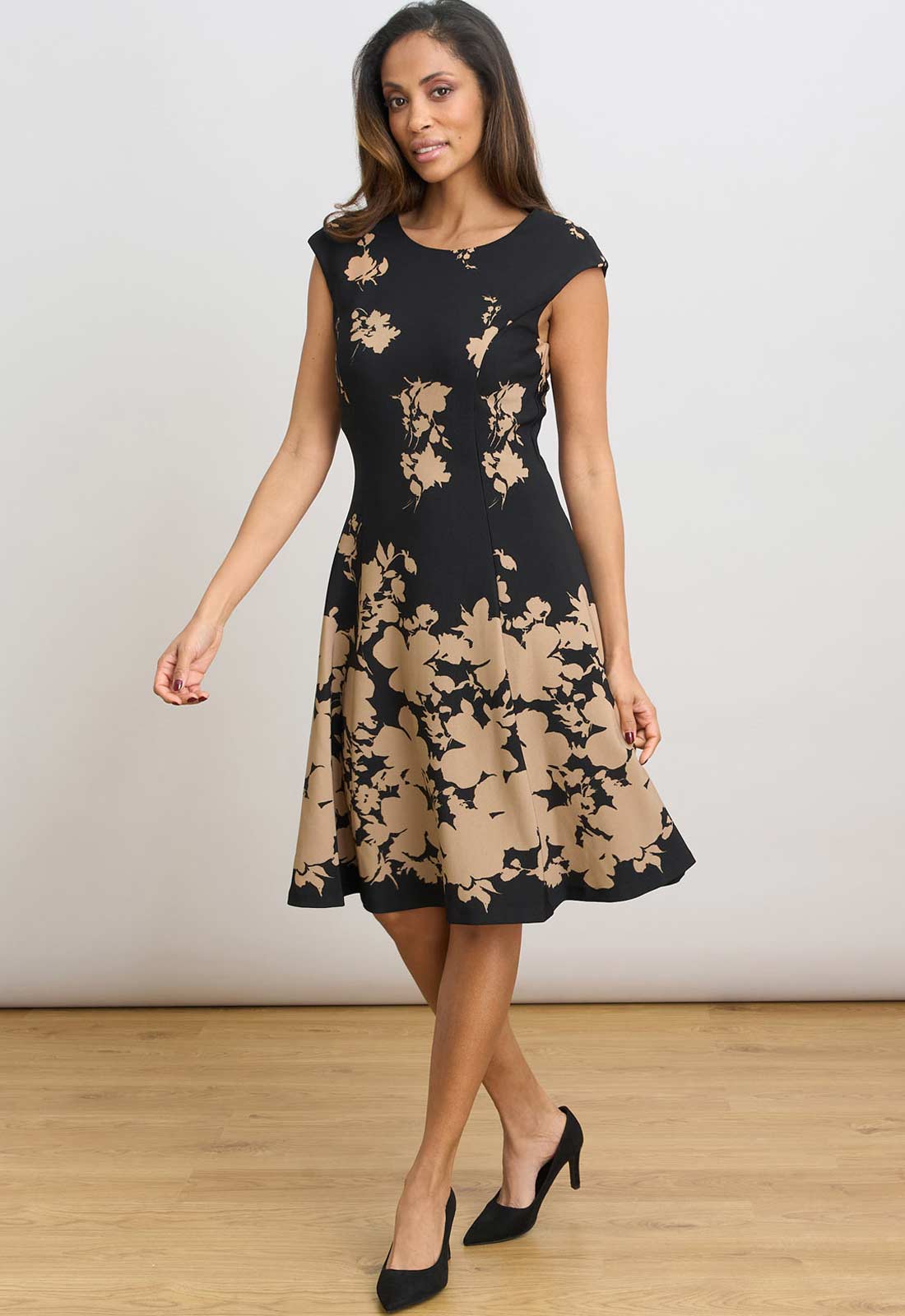 Woman wearing a black and beige floral dress on a plain background