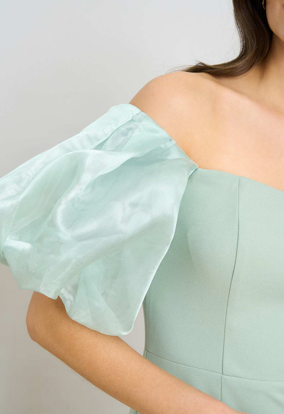 Mint green off-shoulder dress with ruffled sleeves on a plain background