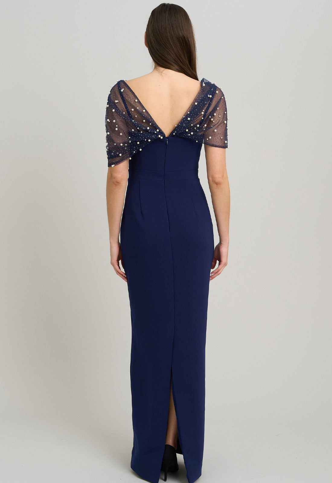 Navy blue evening gown with sheer sleeves and a slit on a gray background