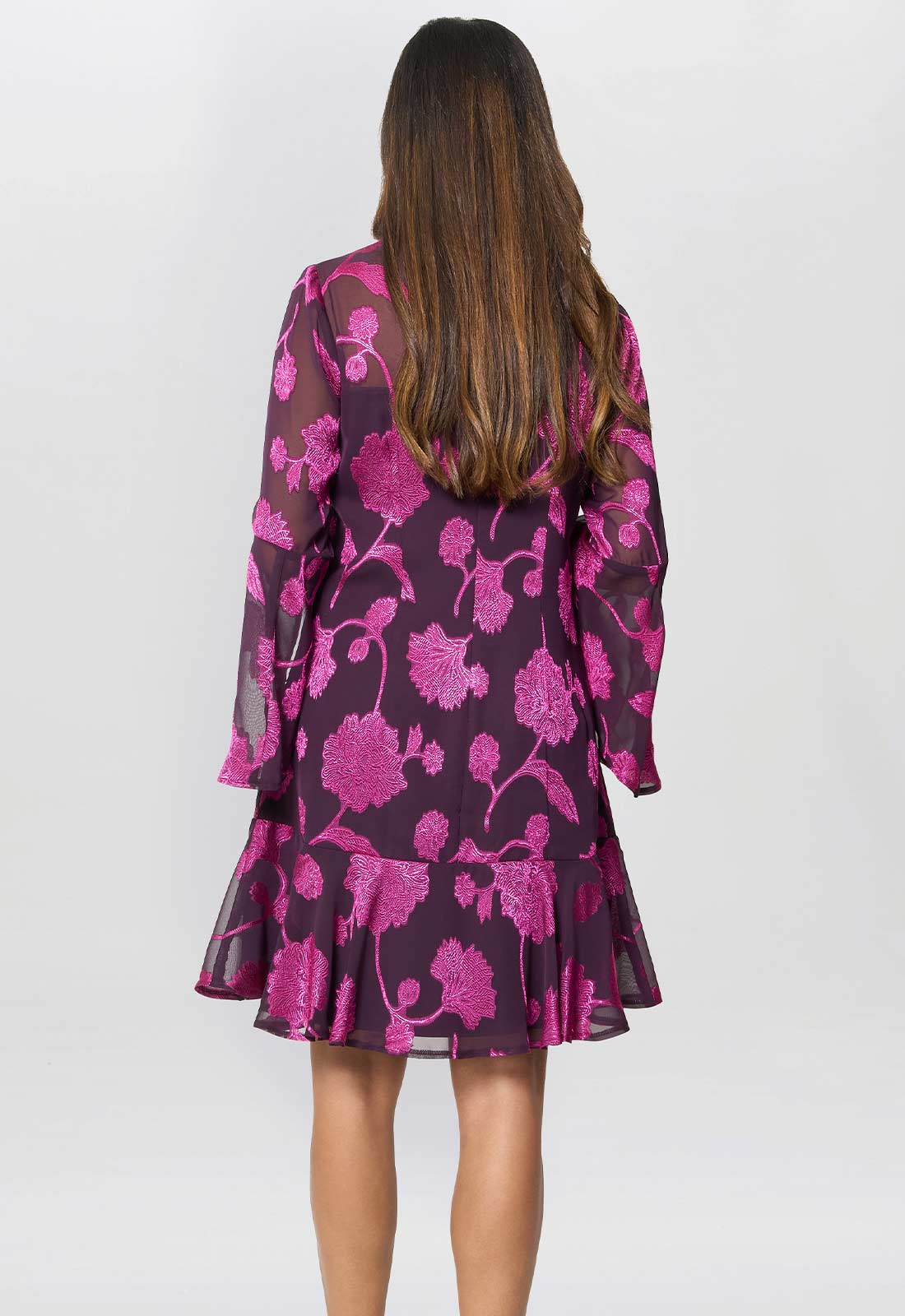 Woman wearing a purple dress with pink floral pattern on a white background