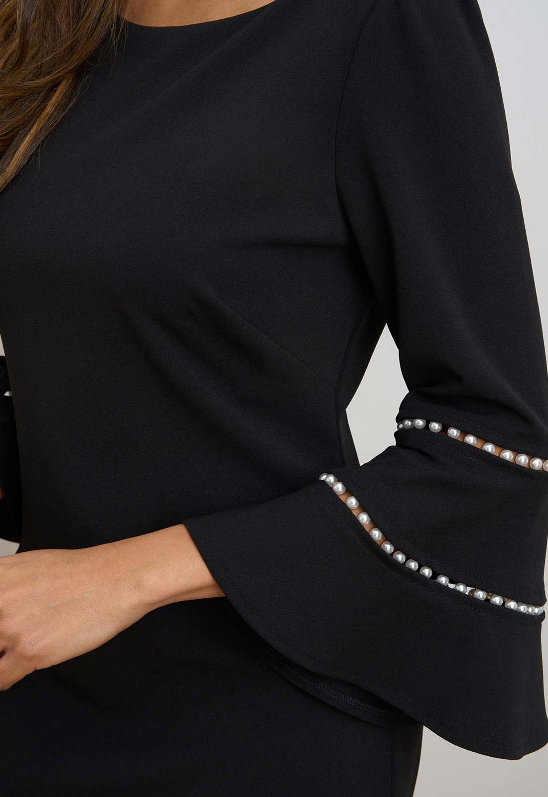 Black long-sleeve top with pearl embellishments on cuffs against a neutral background