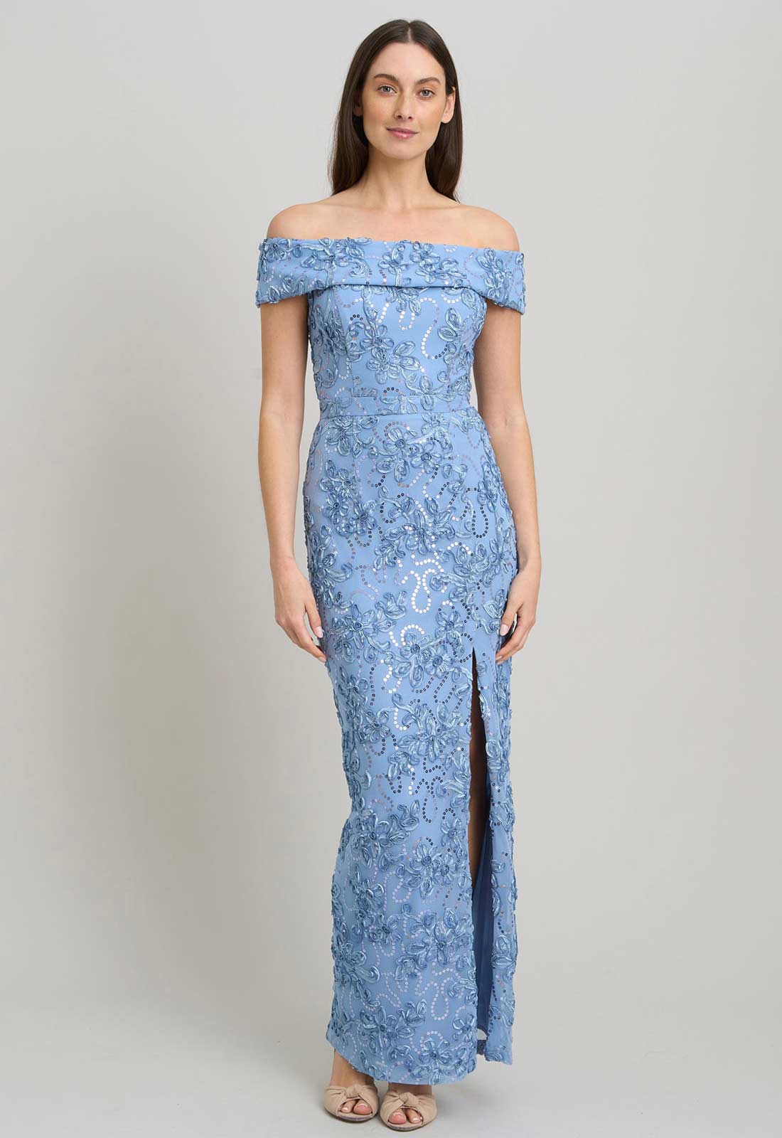 Woman wearing a blue lace off-shoulder gown on a gray background