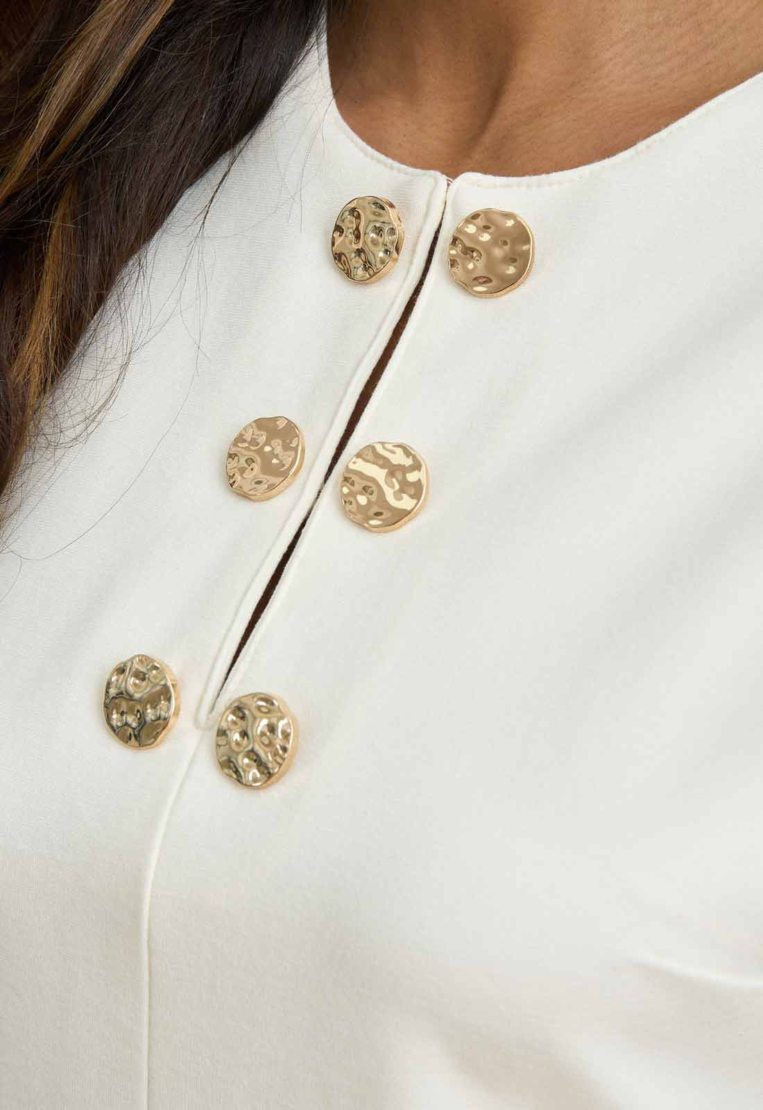 Close-up of a white garment with gold buttons