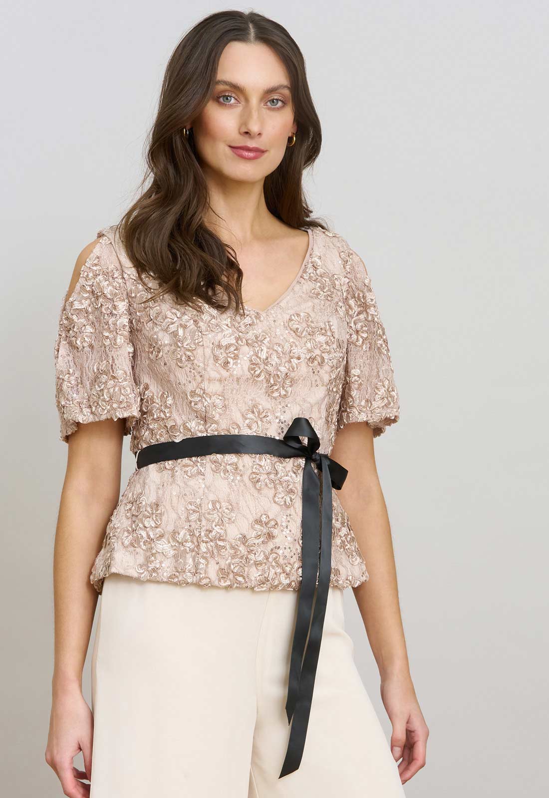 Woman wearing a floral blouse with a black belt against a plain background