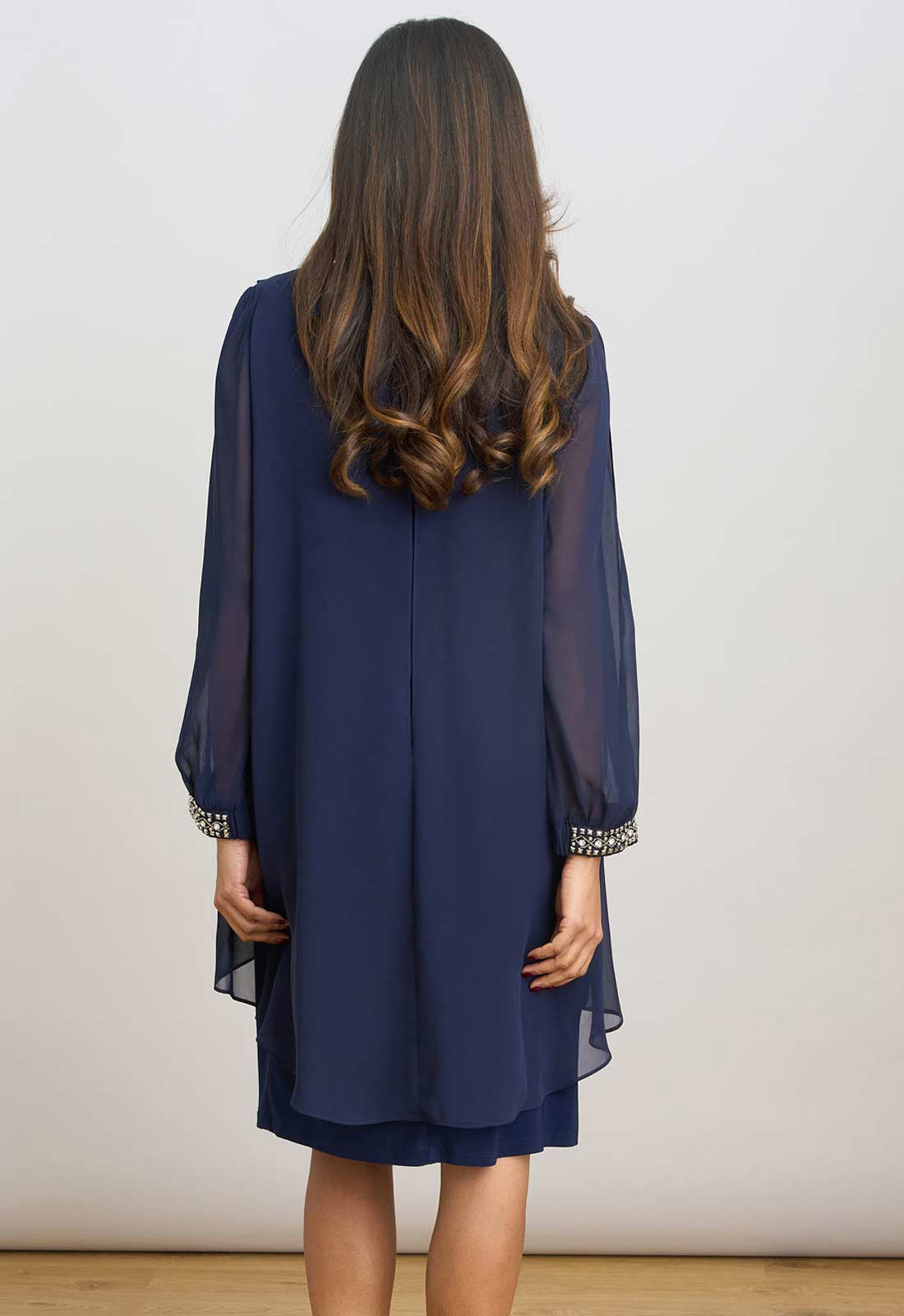 Navy blue dress with sheer sleeves worn by a person against a plain background