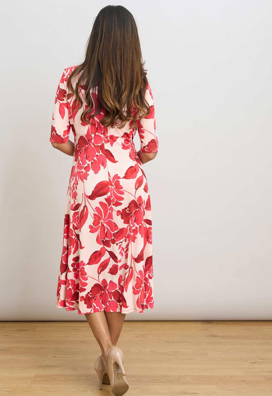 Woman wearing a red floral dress against a white background
