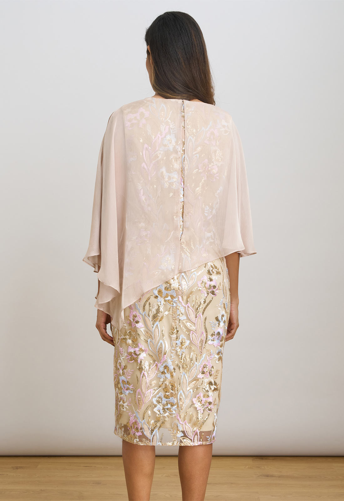 Woman wearing a beige floral dress with a matching shawl against a white background