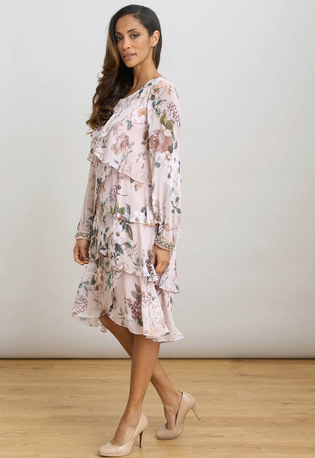 Woman wearing a floral dress with long sleeves on a plain background