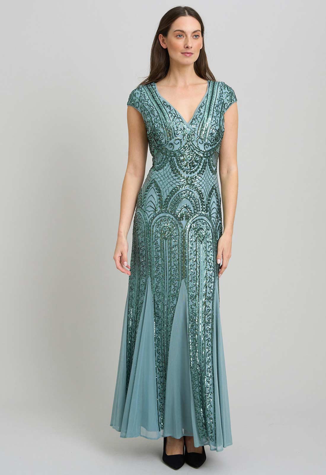 Woman wearing a teal lace dress on a light gray background