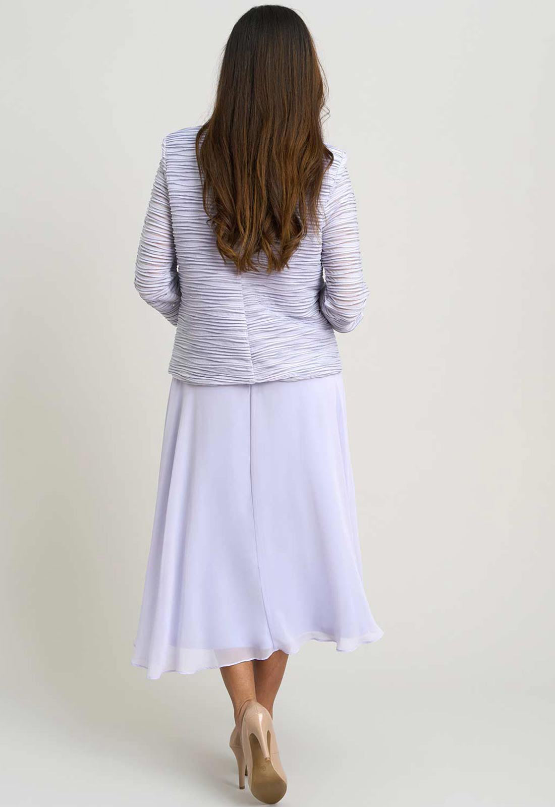 Woman wearing a light purple jacket and white skirt on a plain background