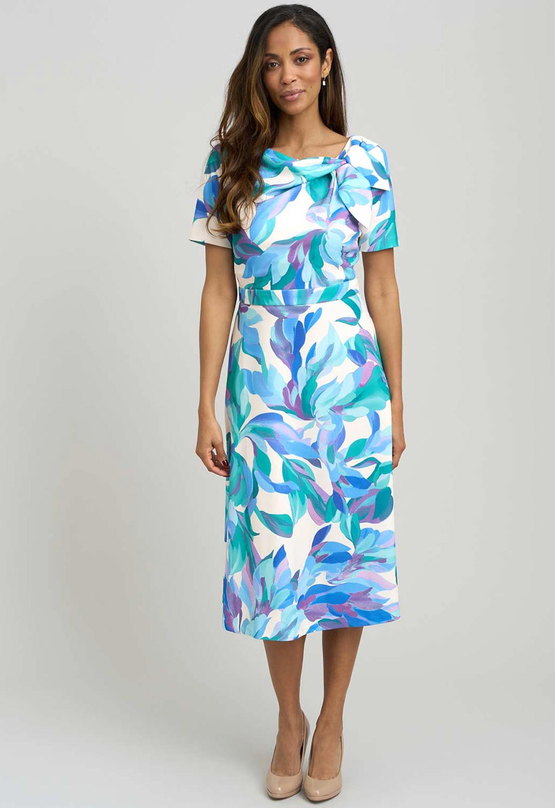 Woman wearing a colorful floral dress on a plain background