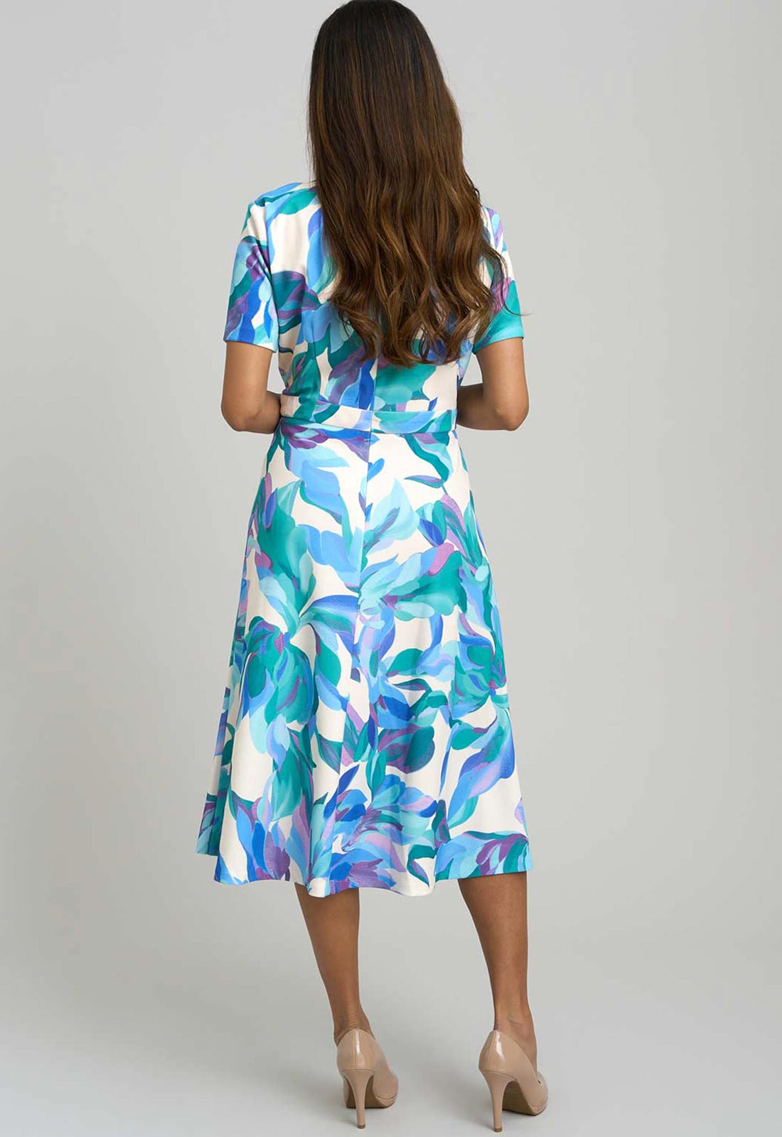 Woman wearing a colorful floral dress on a plain background