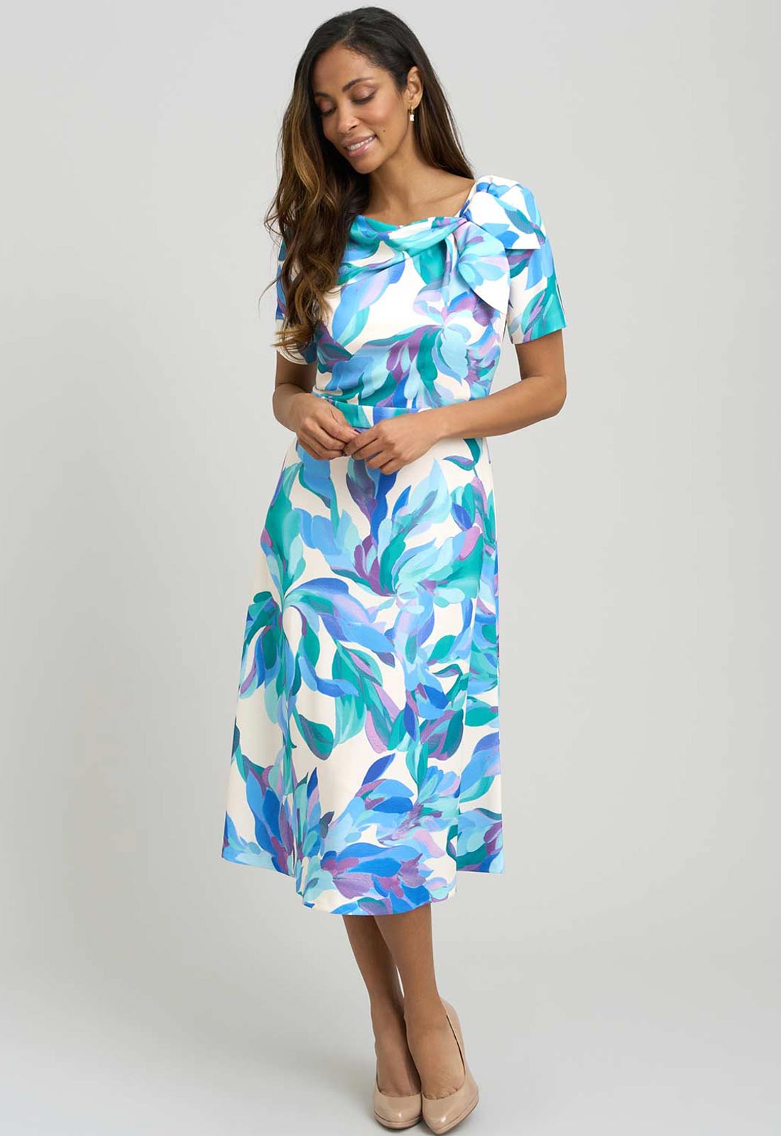 Woman wearing a colorful dress with a leaf pattern on a gray background