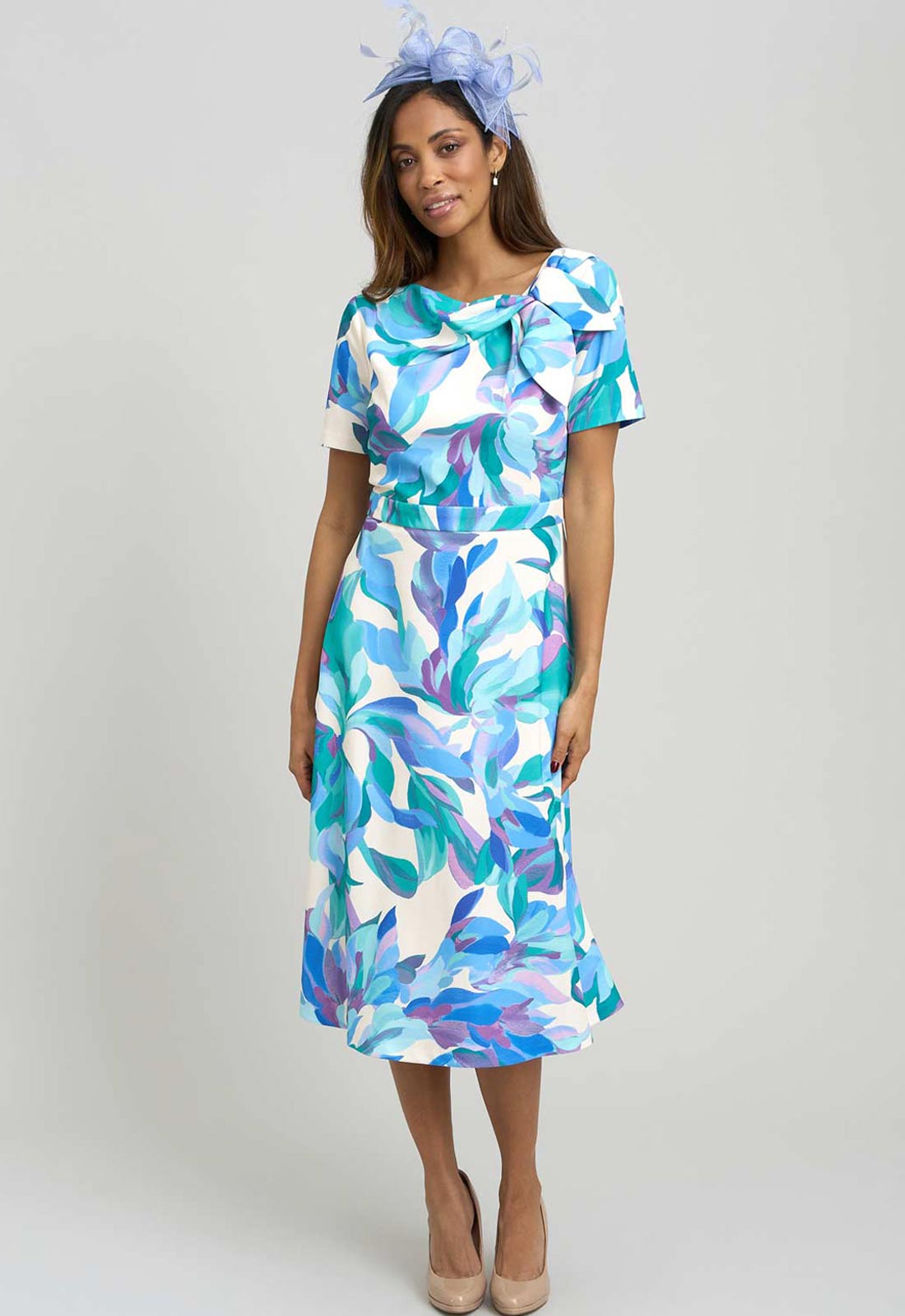 Woman wearing a colorful dress with abstract patterns on a plain background