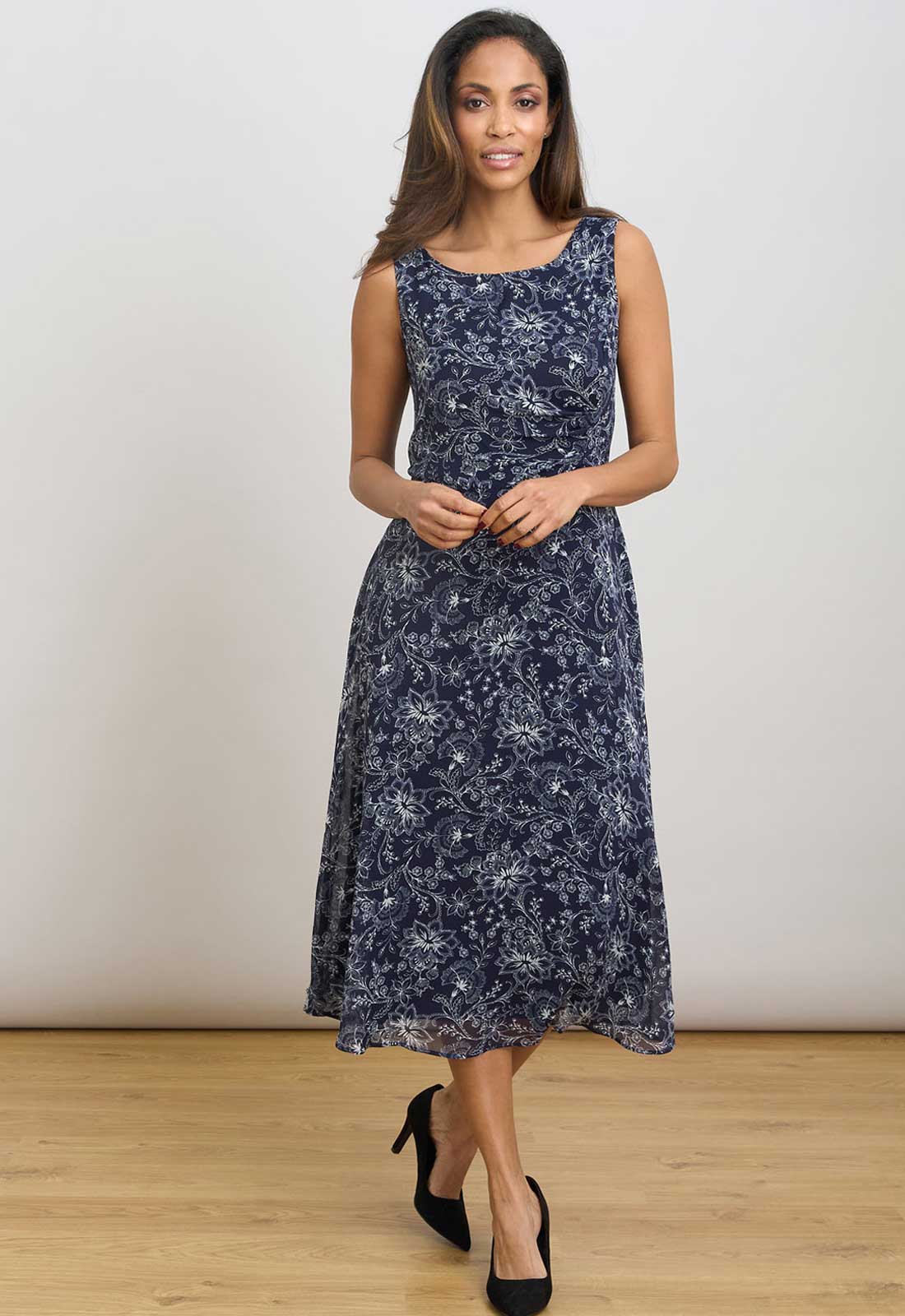 Woman wearing a navy floral dress against a plain background