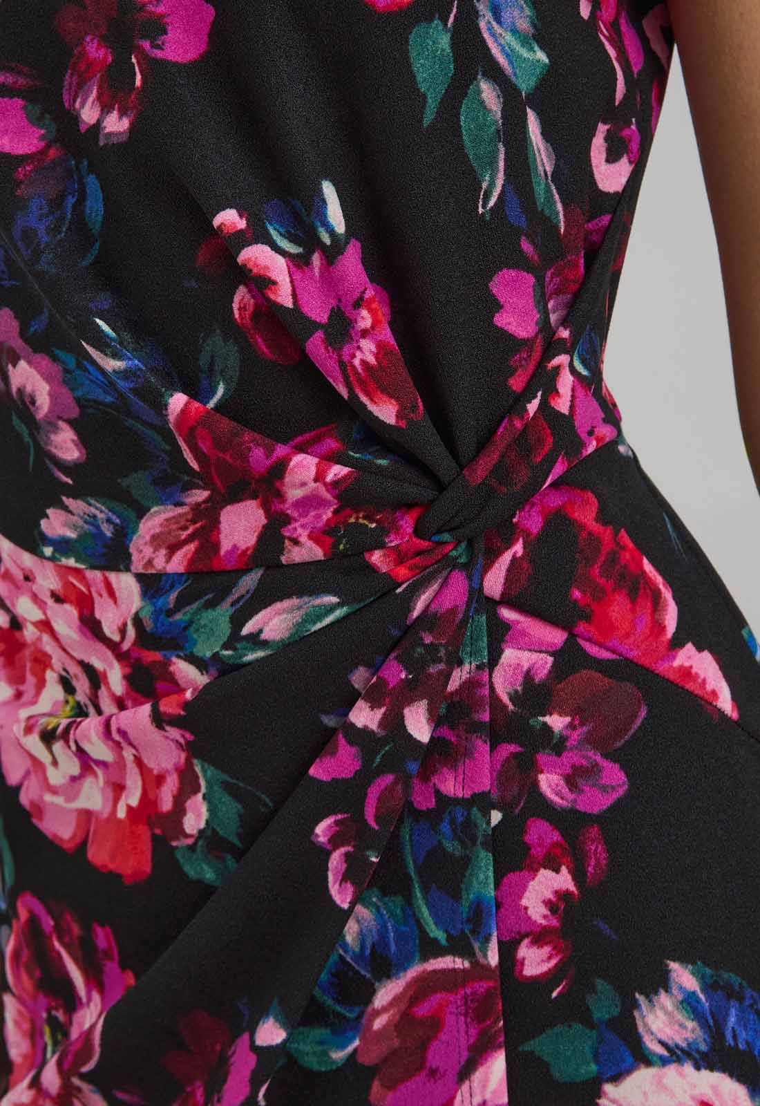 Close-up of a floral dress with a knot detail on a plain background