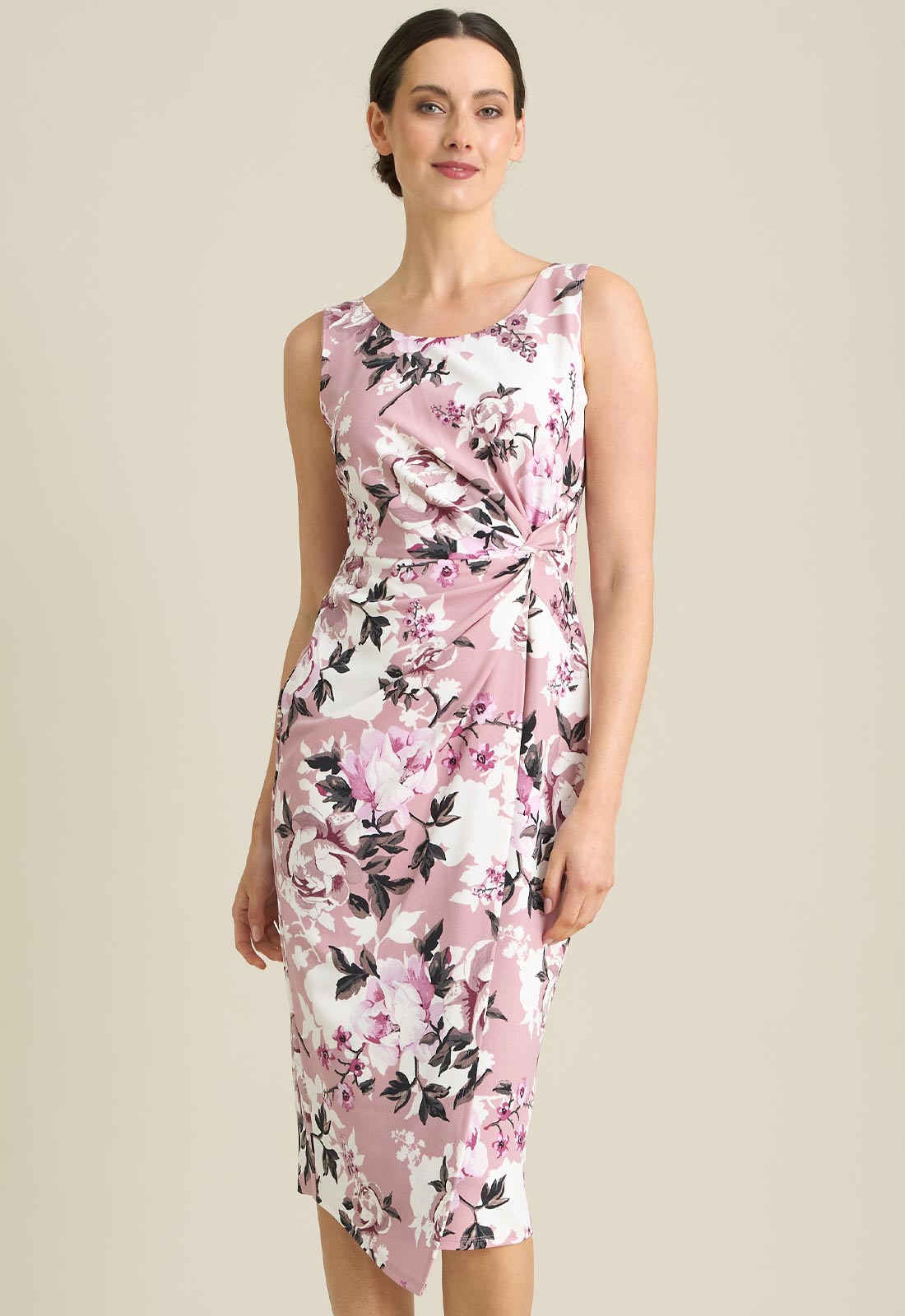 Woman wearing a sleeveless floral dress with pink and black flowers on a beige background