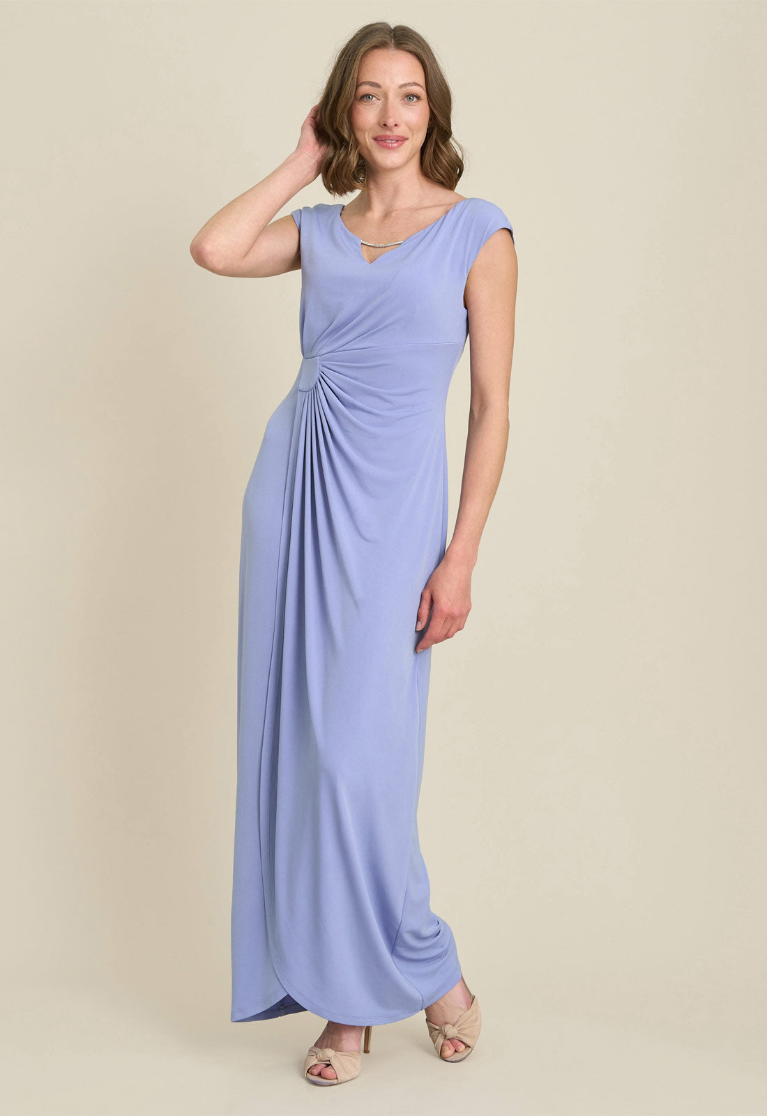 Woman wearing a long light blue dress on a beige background