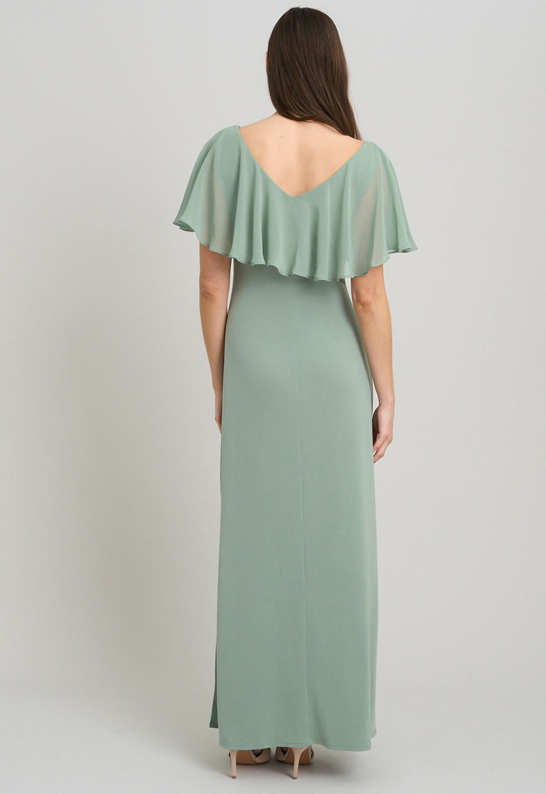 Woman wearing a green dress with ruffled sleeves on a gray background