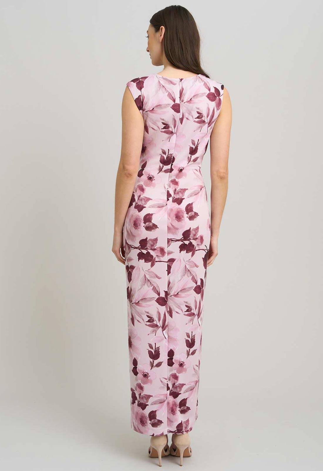 Woman wearing a pink floral jumpsuit on a plain background