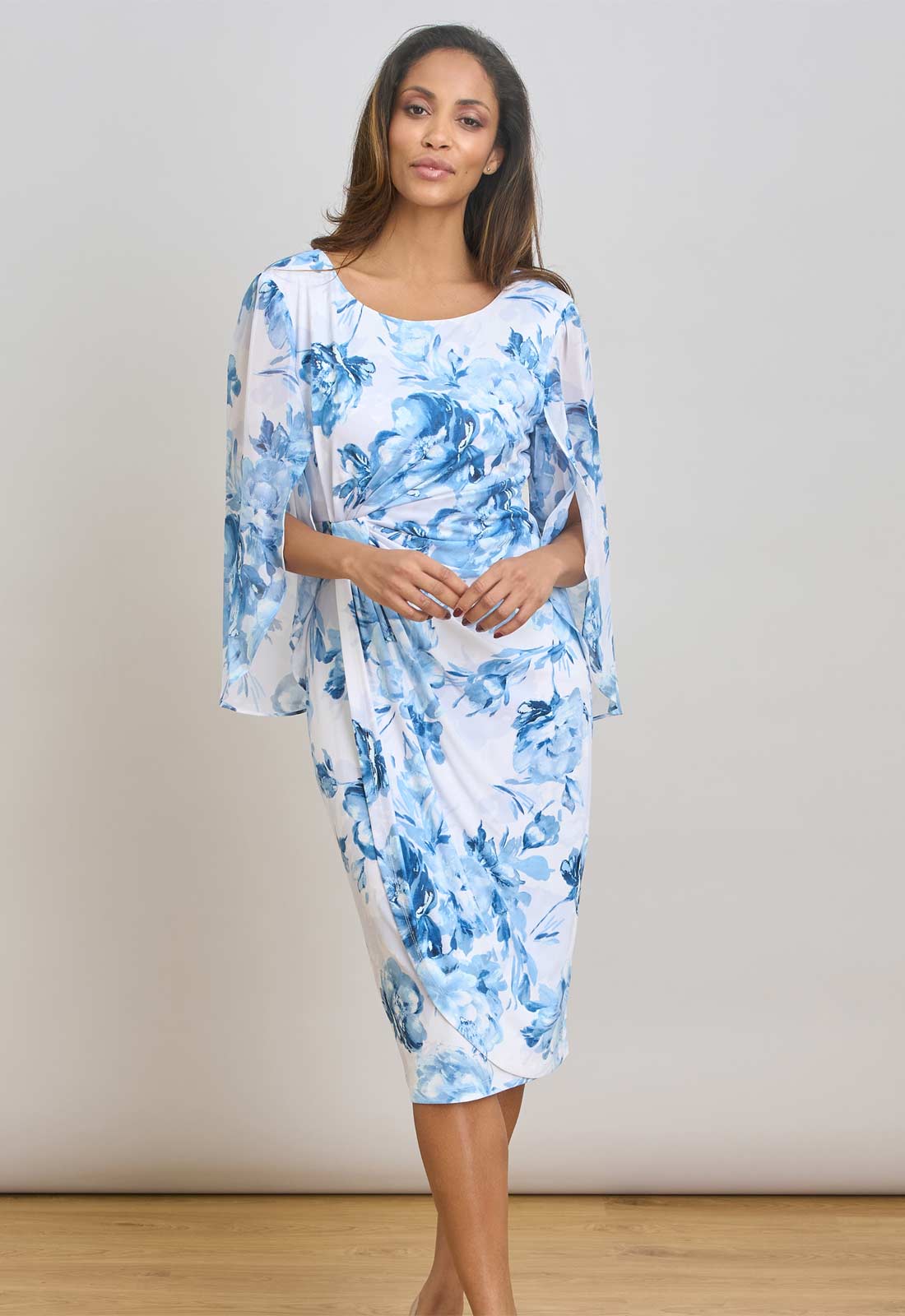 Woman wearing a blue and white floral dress against a plain background