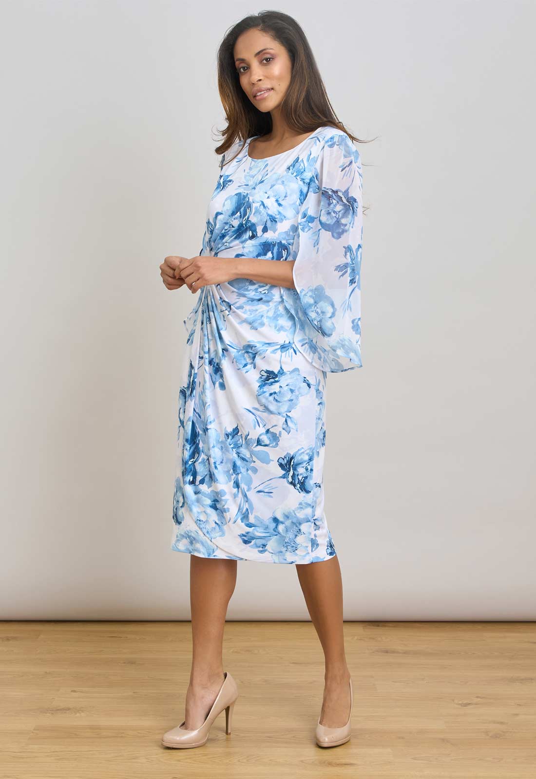 Woman wearing a blue floral dress against a plain background