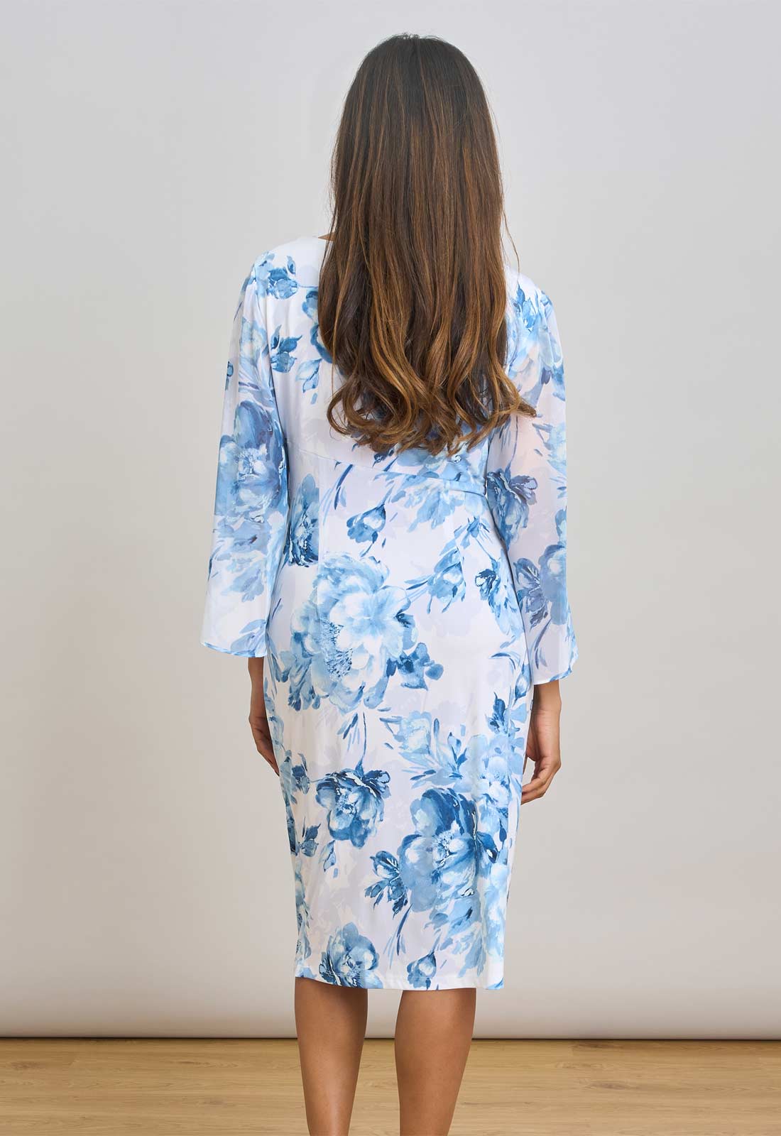 Woman wearing a blue floral dress against a plain background