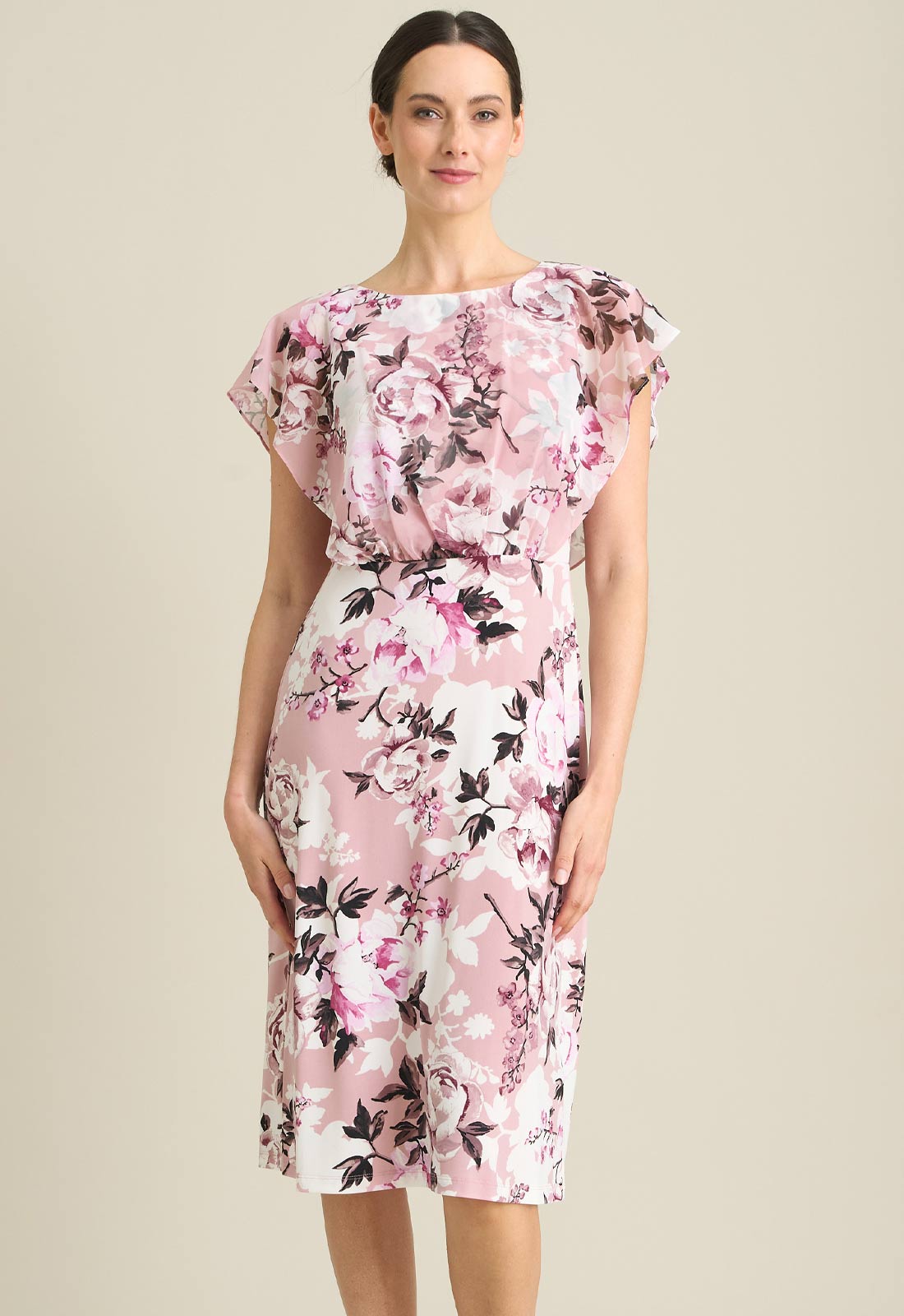 Woman wearing a floral dress with pink and black flowers on a beige background