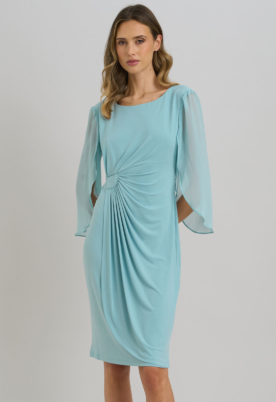 Woman wearing a light blue dress with long sleeves on a plain background