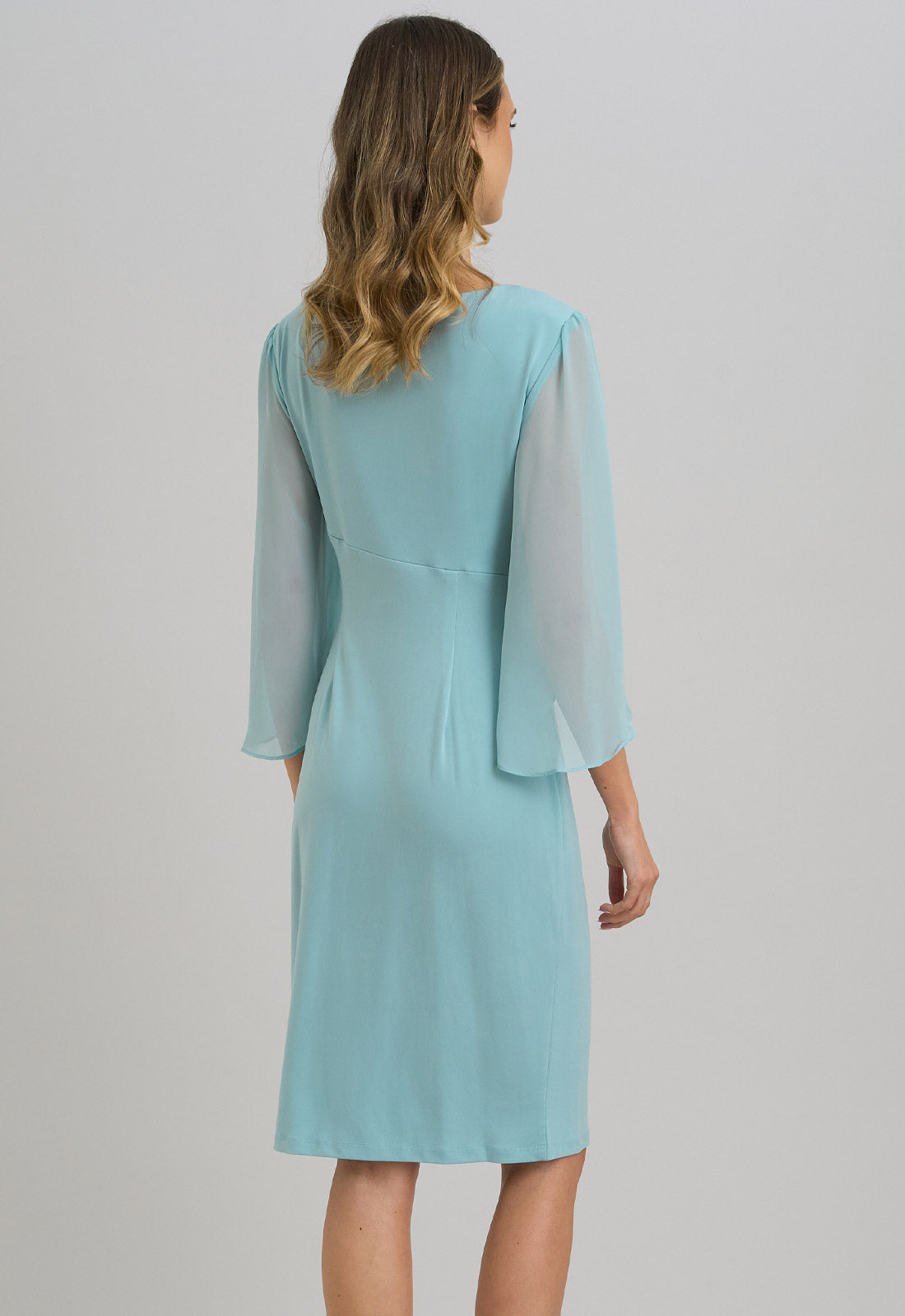 Woman wearing a light blue dress with long sleeves on a gray background