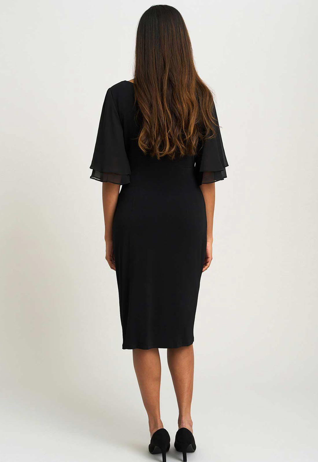 Woman wearing a black dress with sheer sleeves on a white background