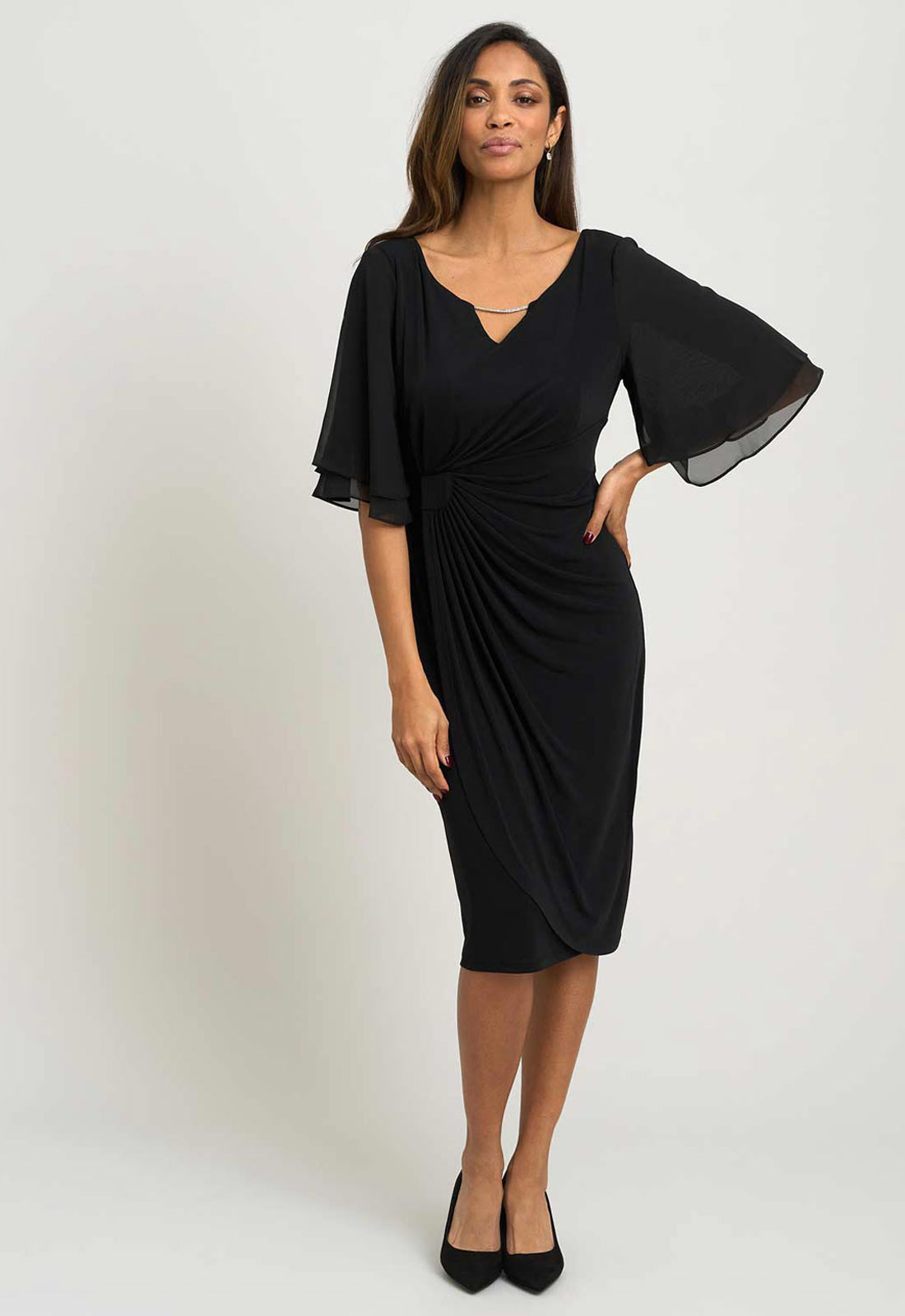 Woman wearing a black dress with bell sleeves on a white background