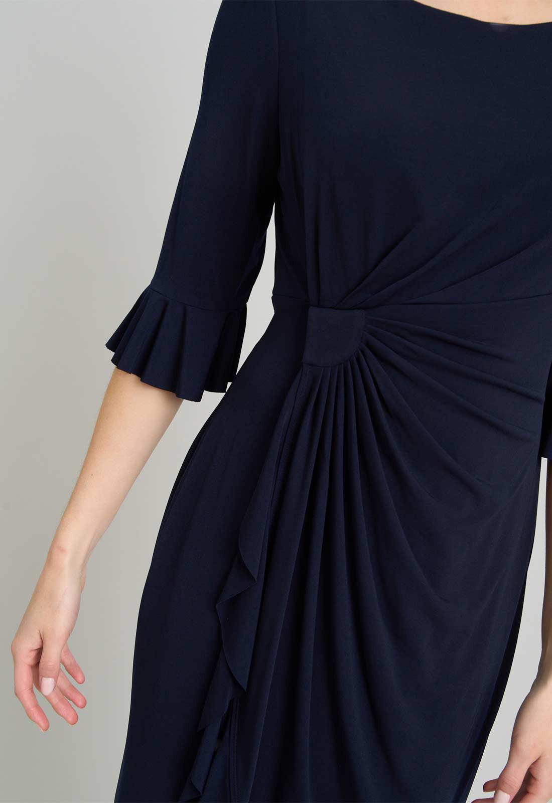 Navy blue dress with a knot detail on a neutral background