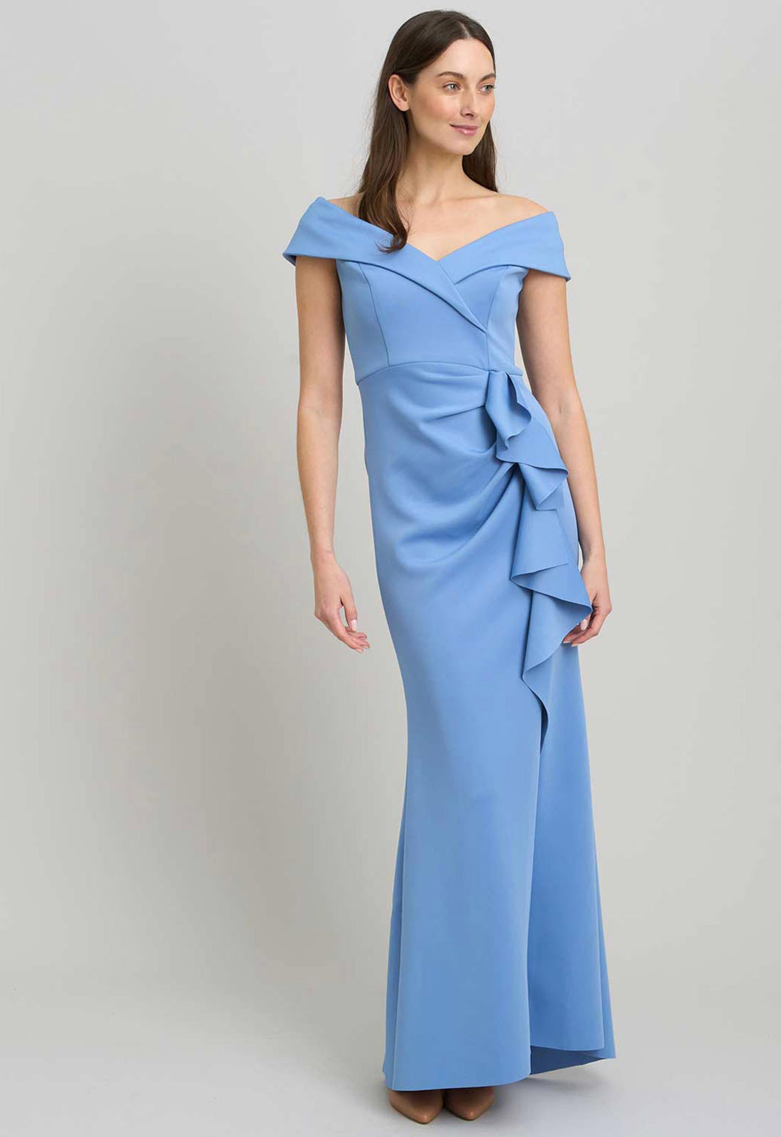 Woman wearing a blue off-shoulder gown with ruffle details on a light gray background
