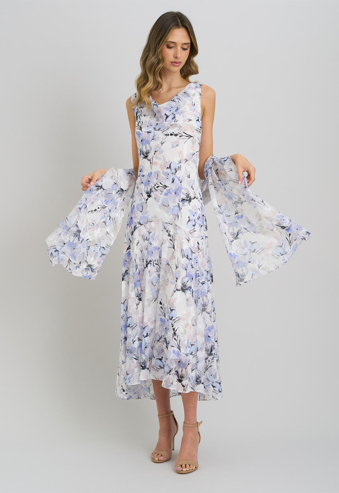 Woman wearing a floral dress with bell sleeves against a plain background