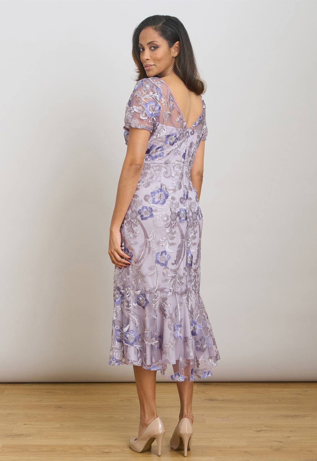 Woman wearing a floral dress against a plain background