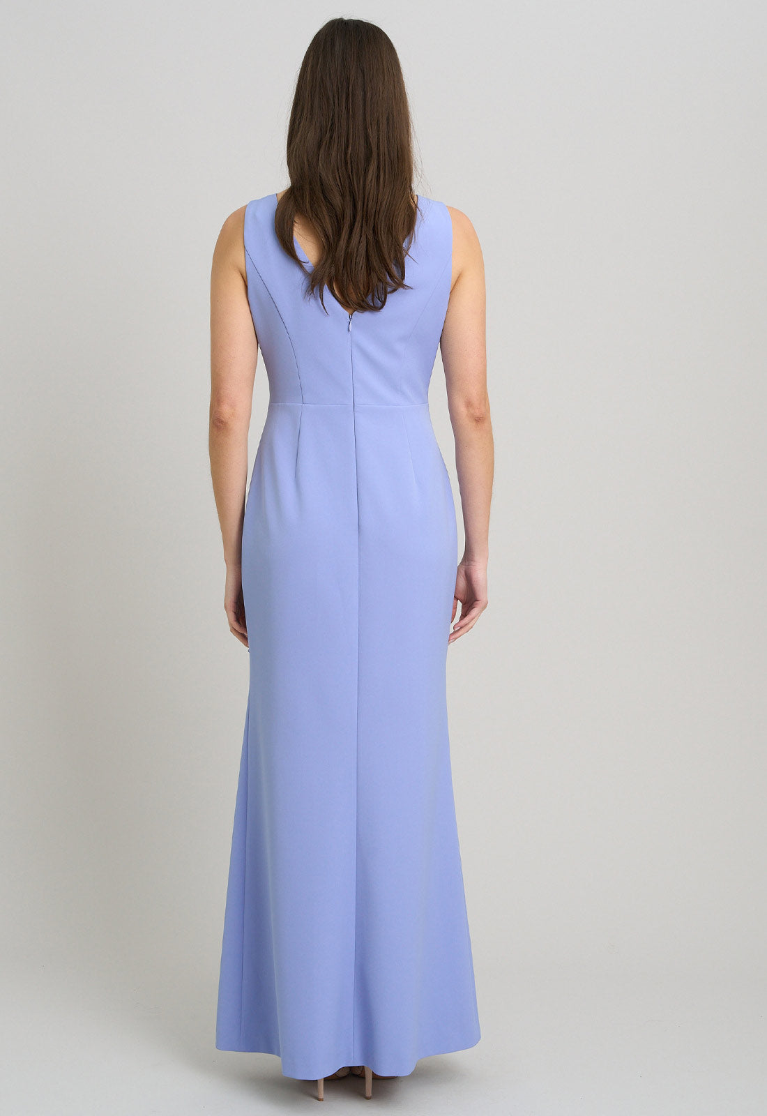 Woman wearing a light blue sleeveless dress against a plain background
