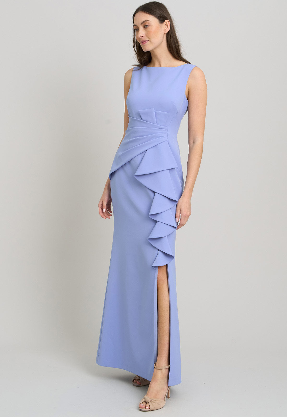 Woman wearing a light blue evening gown with ruffled details on a gray background