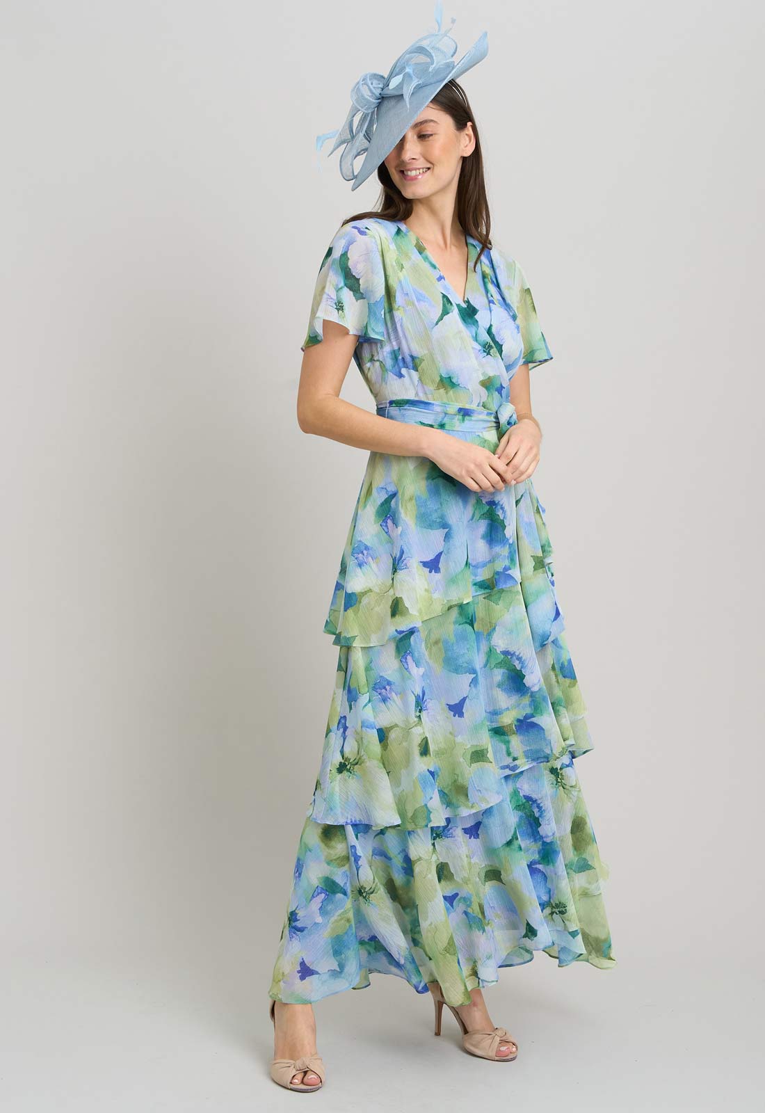 Woman wearing a floral dress with a blue hat on a plain background