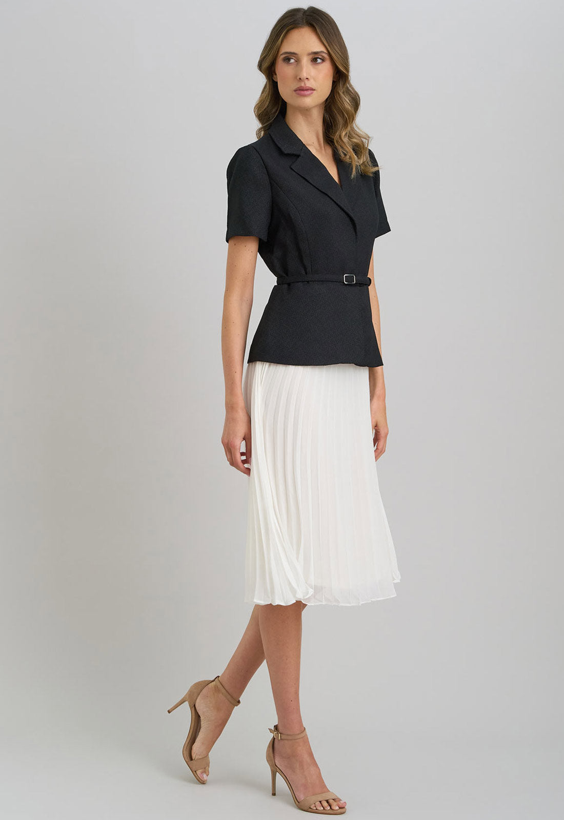 Woman wearing a black blazer and white skirt on a gray background