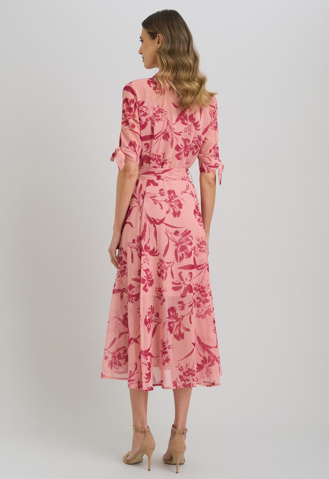 Woman wearing a pink floral dress on a plain background