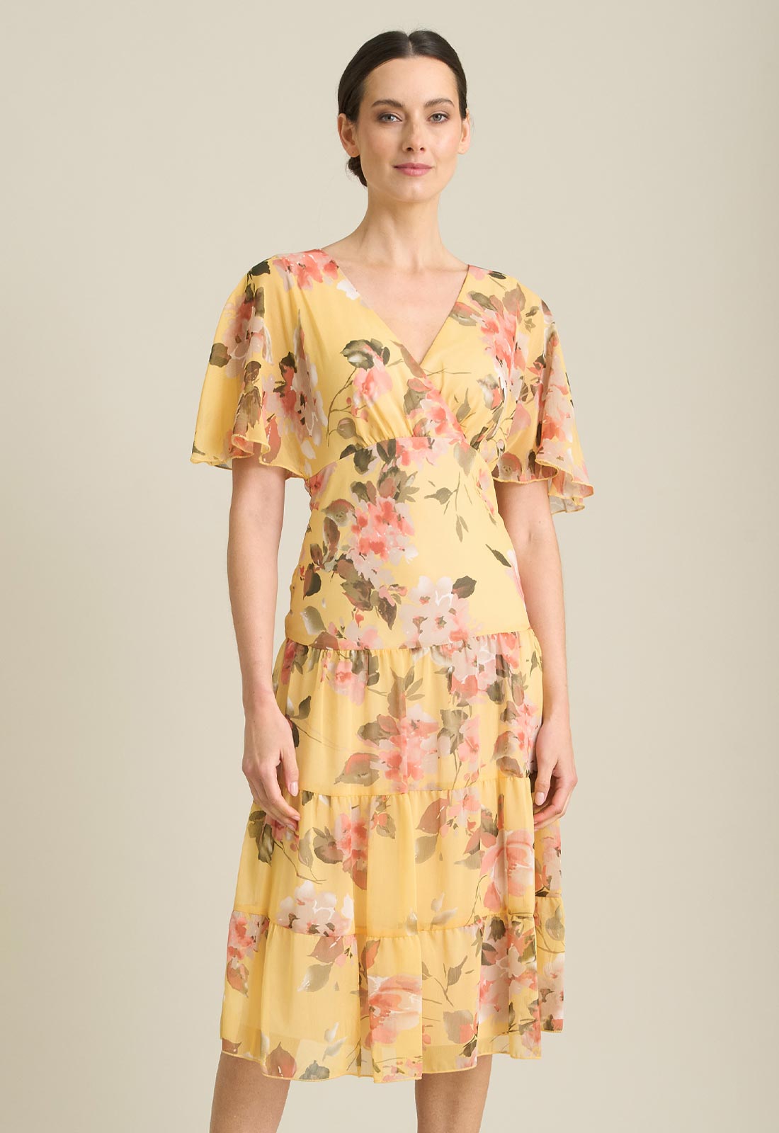 Woman wearing a yellow floral dress against a neutral background