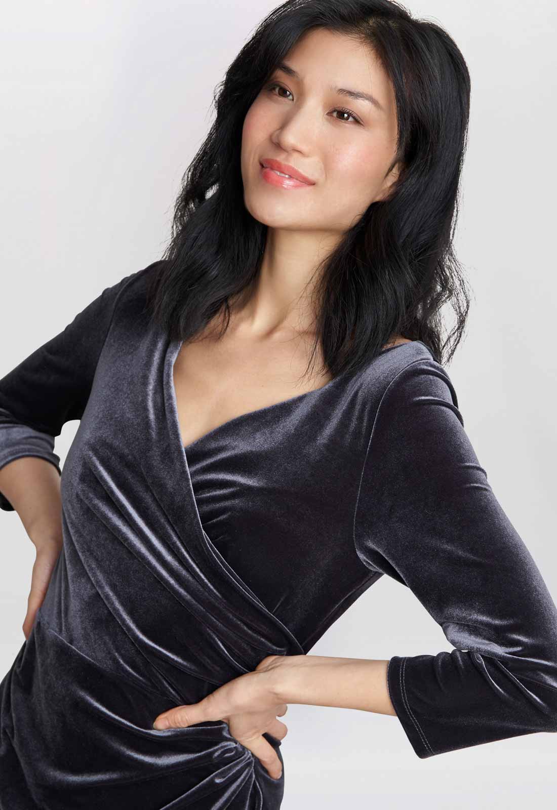 Woman wearing a dark gray velvet dress against a white background