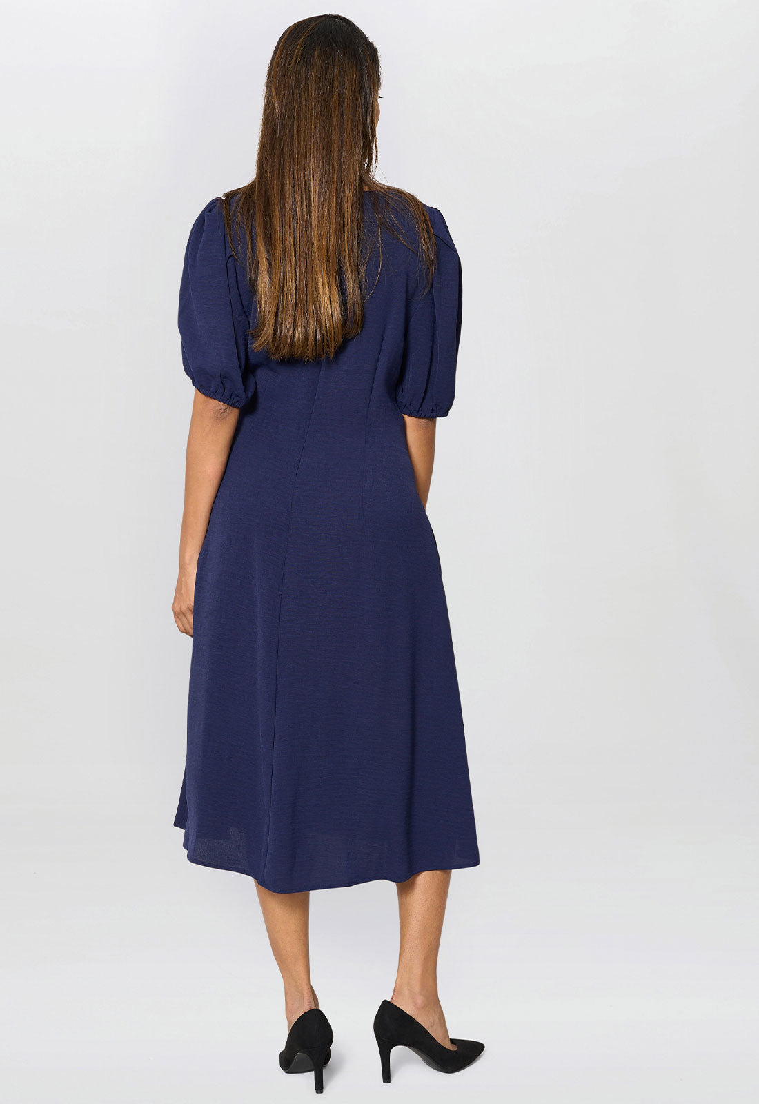 Woman wearing a navy blue dress with puff sleeves on a white background
