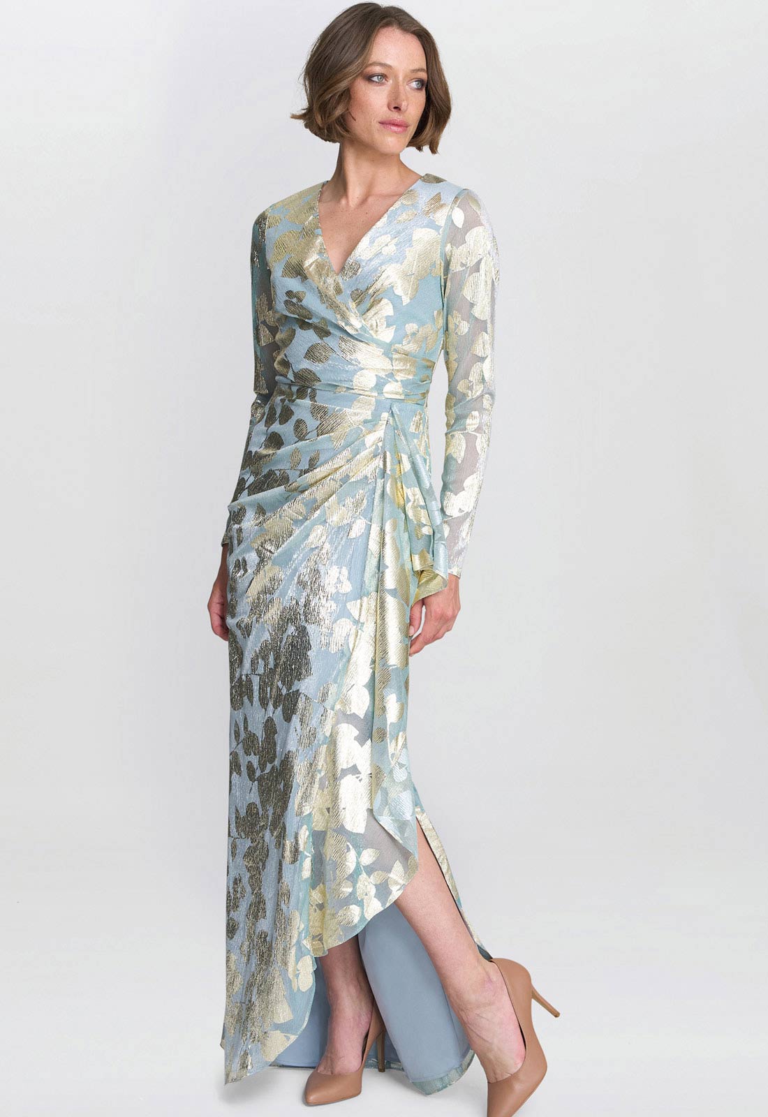 Woman wearing a long, patterned dress with a plain background