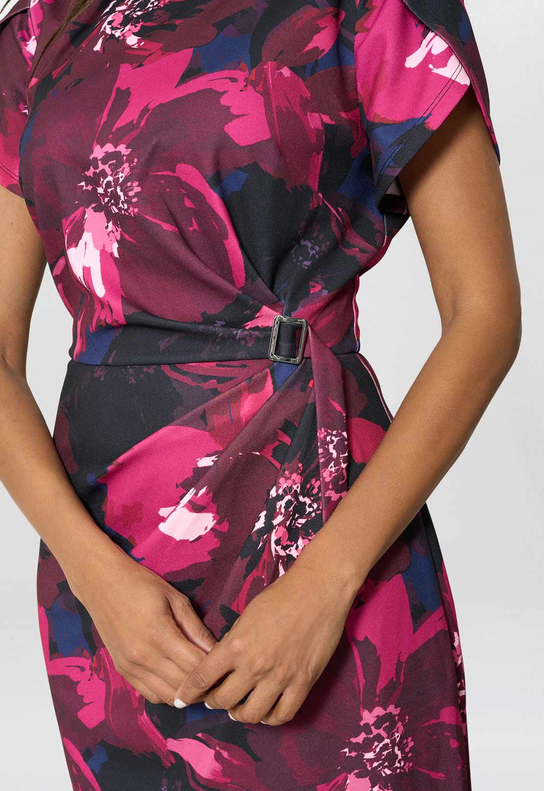 Woman wearing a floral dress with a belt on a white background