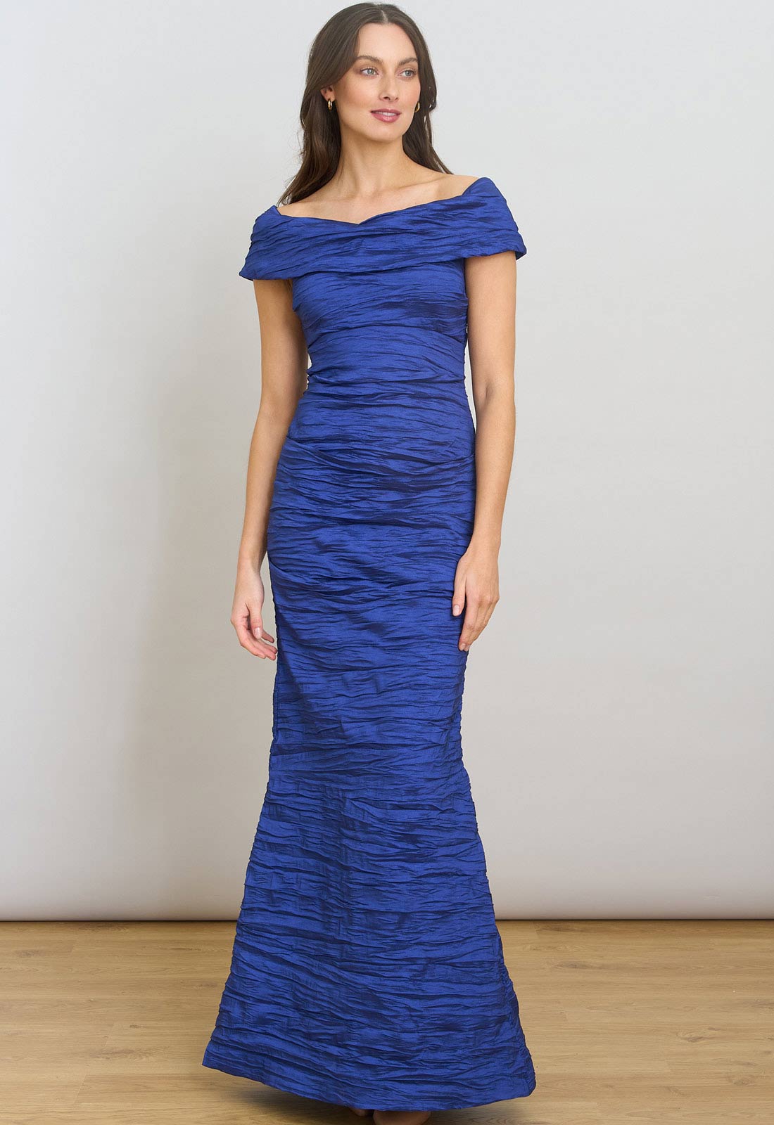 Woman wearing a blue off-shoulder gown against a plain background