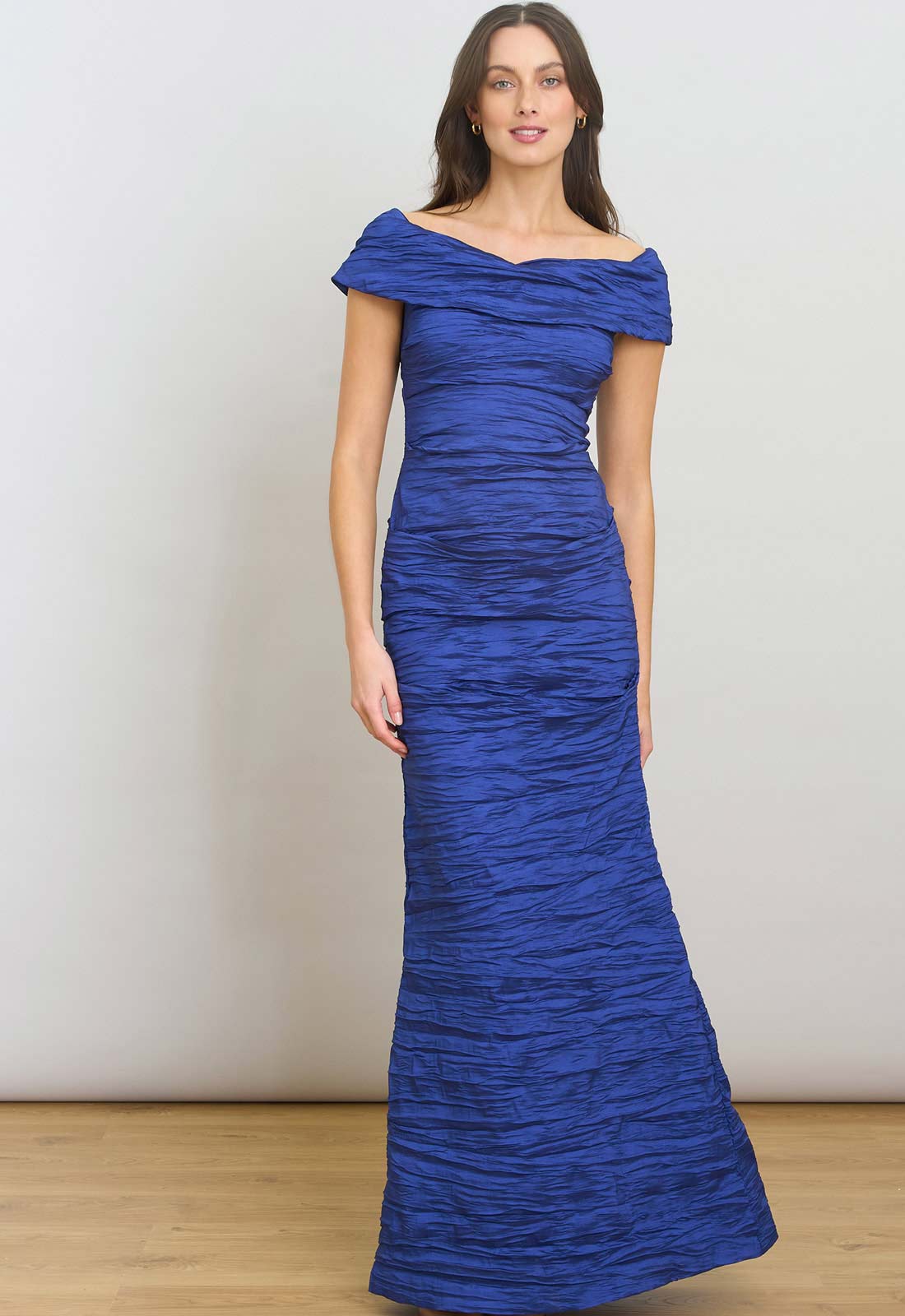 Woman wearing a blue off-shoulder gown against a plain background
