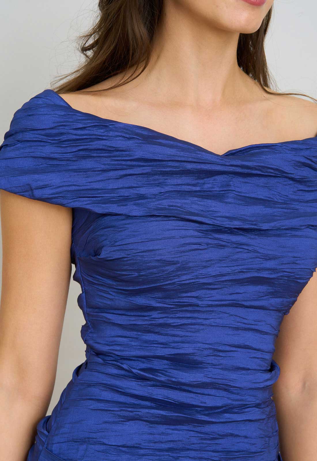 Blue off-shoulder dress worn by a person against a neutral background