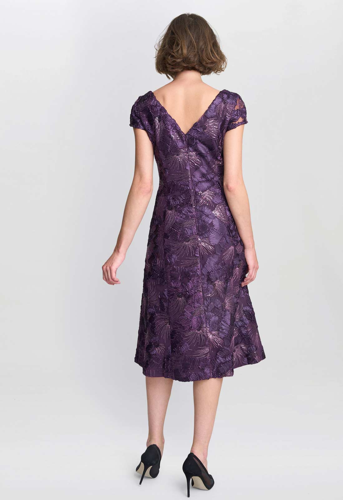 Woman wearing a purple patterned dress on a white background